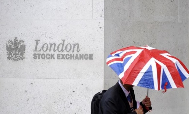 FILE PHOTO: A worker shelters from the rain as he passes the London Stock Exchange in the City of London at lunchtime October 1, 2008. REUTERS/Toby Melville/File Photo
