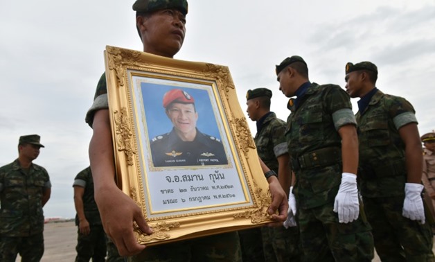 A Royal Thai Navy member carries a portrait of Saman Gunan, an ex-navy SEAL who died after running out of oxygen while on a mission to rescue the 12 boys and their coach trapped deep inside Thailand's Tham Luang cave
