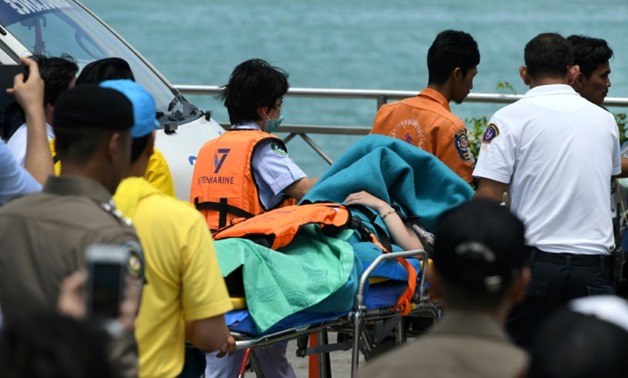 Emergency personnel transfer a passenger from the sunken tourist boat - AFP
