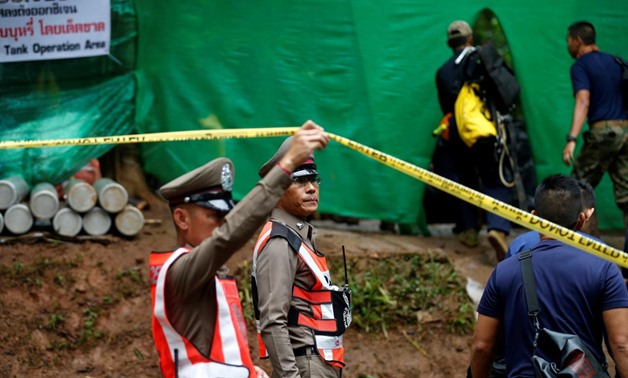 A police officer raises a police tape as divers arrive at the Tham Luang cave complex, where 12 schoolboys and their soccer coach are trapped inside a cave - Reuters