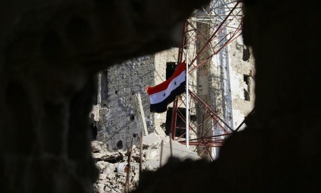 The Syrian national flag flies in the midst of damaged buildings in Daraa-al-Balad, an opposition-held part of the southern city of Daraa, on July 12, 2018
