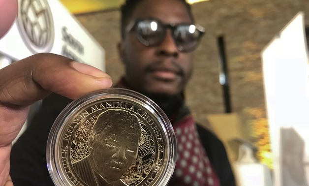 Zimbabwe-born Sindiso Nyoni holds a 1-ounce pure gold 5 rand coin that he designed, as the South African Reserve Bank (SARB) launched a set of limited edition bank notes and gold coins to mark the 100th anniversary of the birth of Nelson Mandela, in Preto