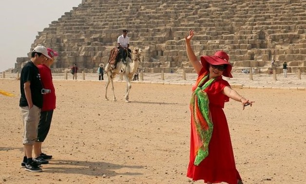 A tourist poses in front of a policeman on a camel at the pyramids plateau - Reuters