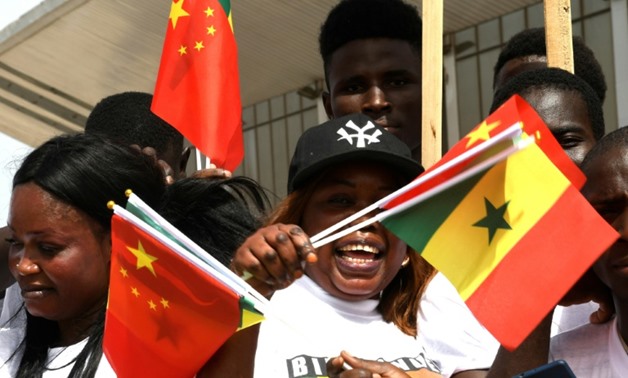Young Senegalese wave flags to mark the arrival of President Xi on a state visit with China the west African nation's second biggest trading partner behind France, its firms having embarked on a slew of major infrastructure projects
