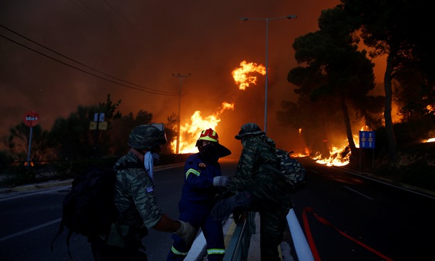 Firefighters and soldiers fall back as a wildfire burns in the town of Rafina, near Athens, Greece, July 23, 2018. REUTERS/Costas Baltas
