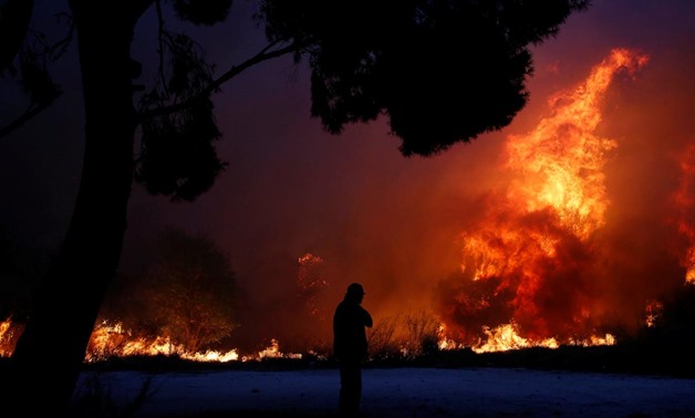 A man looks at the flames as a wildfire burns in the town of Rafina, near Athens, Greece, July 23, 2018. REUTERS/Costas Baltas. “
