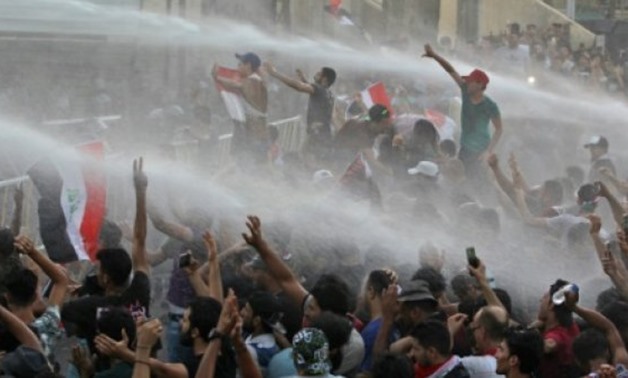 © AFP | Iraqi protesters waving national flags are sprayed with water cannon by security forces during a demonstration against unemployment and a lack of basic services in Baghdad's Tahrir Square on July 20, 2018