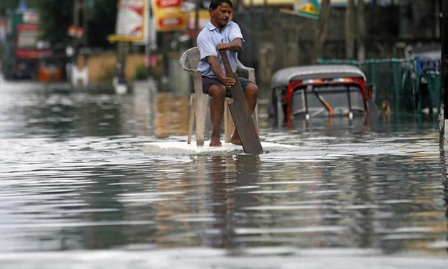 A man sits on a chair as he uses a piece of styrofoam to move through a flooded road in Wellampitiya, Sri Lanka May 21, 2016. REUTERS/Dinuka Liyanawatte
