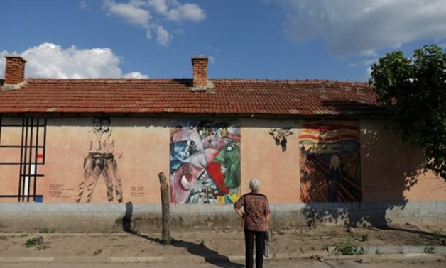A local villager looks at murals on the wall of a house in the village of Staro Zhelezare, Bulgaria, August 4, 2018. REUTERS/Stoyan Nenov.