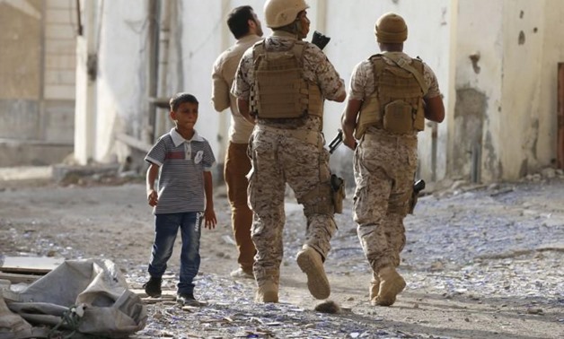 A boy walks past soldiers from the Saudi-led coalition patrolling a street in Yemen's southern port city of Aden September 26, 2015. REUTERS/Faisal Al Nasser