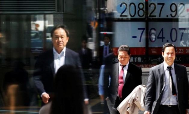 People walk past an electronic board showing Japan's Nikkei average outside a brokerage in Tokyo, Japan, March 23, 2018. REUTERS/Toru Hanai/File Photo
