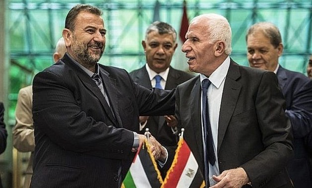 Fatah's Azzam al-Ahmad, right, and Saleh al-Arouri of Hamas shake hands after signing a reconciliation deal in Cairo, on October 12, 2017, as the two rival Palestinian movements ended their decade-long split following negotiations overseen by Egypt. (AFP/