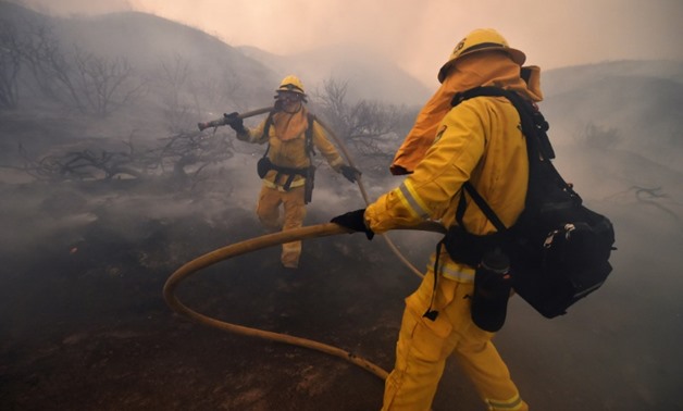 Riverside County firefighters douse embers after flames tore down a hillside in a residential neighborhood during the Holy Fire in Lake Elsinore, California, on August 9, 2018
