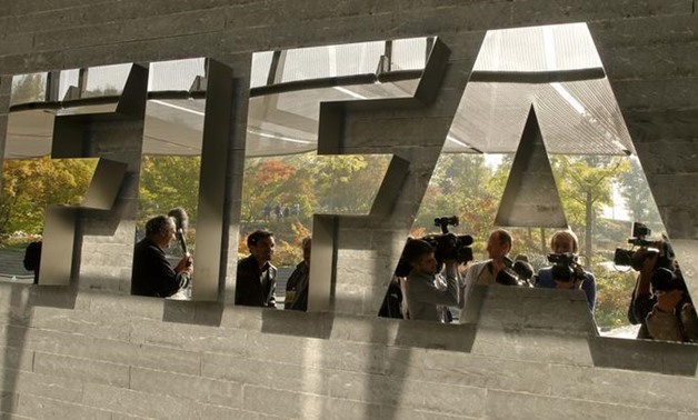 Journalists are reflected in a logo at the FIFA headquarters after a meeting of the executive committee in Zurich October 4, 2013. REUTERS/Arnd Wiegmann
