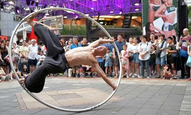 Taiwanese American street artist Isaac Hou began performing with a Cyr wheel because he wanted to move away from juggling with fire - AFP
