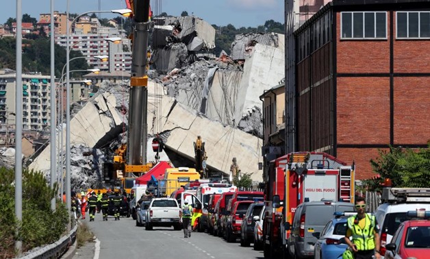 Firefighters and rescue workers stand at the site of a collapsed Morandi Bridge in the port city of Genoa, Italy August 15, 2018. REUTERS/Stefano Rellandini
