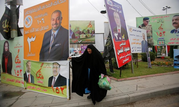 A woman walks past campaign posters of candidates ahead of parliamentary election, in Baghdad, Iraq April 22, 2018. REUTERS/Khalid al Mousily
