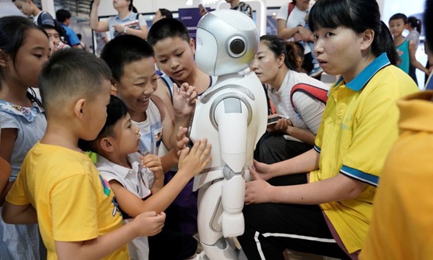 Children play with an iPal robot at Avatarmind's booth at the World Robot Conference (WRC) in Beijing, China August 17, 2018. REUTERS/Jason Lee