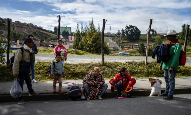 Venezuelan migrant Mariangela Ascano (2-L, behind) pauses with relatives and friends on the Pan-American Highway in Ipiales, Colombia, on the way to Ecuador,
