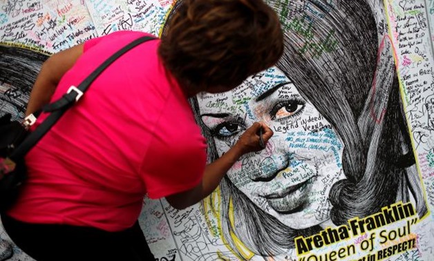 A woman writes on a large drawing of Aretha Franklin outside the Charles H. Wright Museum of African American History on the second day of a public viewing of the late singer in Detroit, Michigan, U.S., August 29, 2018. REUTERS/Mike Segar.
