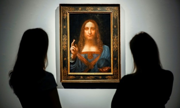 Christie's employees pose in front of a painting entitled Salvator Mundi and attributed to Leonardo da Vinci at a photocall at the auction house in central London on October 22, 2017 a month ahead of its sale.