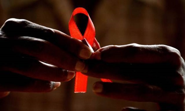 A man holds a red ribbon to mark World Aids Day, at the entrance of Emilio Ribas Hospital, in Sao Paulo Dec. 1, 2014 – Reuters