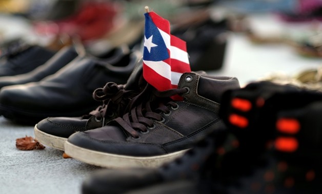 View of a Puerto Rican flag placed on a pair of shoes among hundreds displayed in memory of those killed by Hurricane Maria in front of the Puerto Rican Capitol, in San Juan on June 1, 2018
