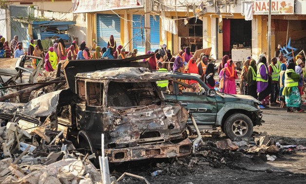 People gather near burnt vehicles a day after a truck bomb exploded in the center of Mogadishu on Sunday - AFP
