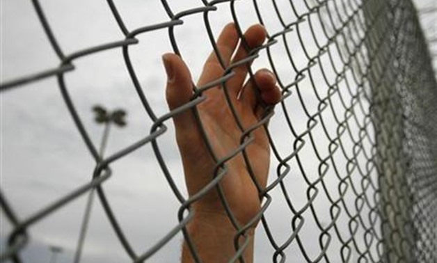 An inmate serving a jail sentence rests his hand on a fence at Maricopa County's Tent City jail in Phoenix July 30, 2010. REUTERS/Joshua Lott
