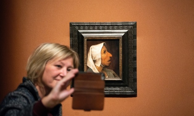 A visitor takes a selfie with the painting 'Head of a Peasant Woman' at the world's first monograph exhibition dedicated to Flemish master Pieter Bruegel the Elder in Vienna.