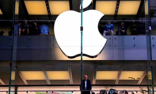 A customer stands underneath an illuminated Apple logo as he looks out the window of the Apple store located in central Sydney, Australia, May 28, 2018. REUTERS/David Gray
