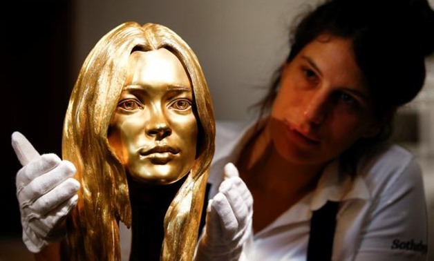 A Sotheby's employee poses with a bust of Kate Moss in solid 18-carat gold during a photocall for 'The Midas Touch' collection at Sotheby's in London, Britain, October 12, 2018. REUTERS/Henry Nicholls.