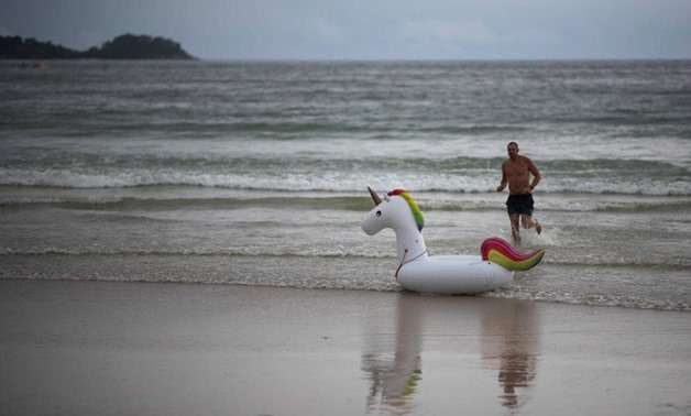 A tourist runs after his lose unicorn-floaty at the Patong Beach in Phuket on October 12, 2018. (AFP)