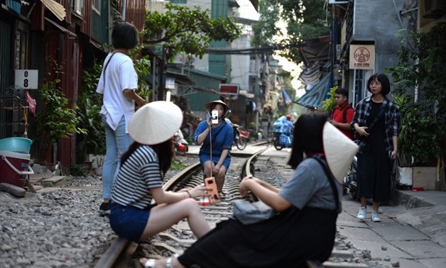 Tourists pose for a photo while sitting on a railway track passing through an old residential district in central Hanoi on Oct. 21, 2018. Nhac NGUYEN / AFP (AFP/Nhac Nguyen)
