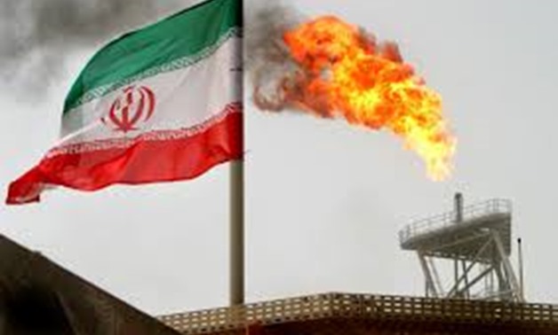 A gas flare on an oil production platform in the Soroush oil fields is seen alongside an Iranian flag in the Persian Gulf, Iran, July 25, 2005. REUTERS/Raheb Homavandi/File Photo.