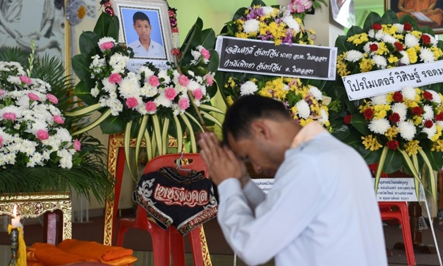 A mourner prays in front of a portrait of 13-year-old Muay Thai boxer Anucha Tasako next to his coffin during a funeral at a Buddhist temple in Samut Prakan province on November 14, 2018. Thais have reacted with shock and anger after Tasako died during a 