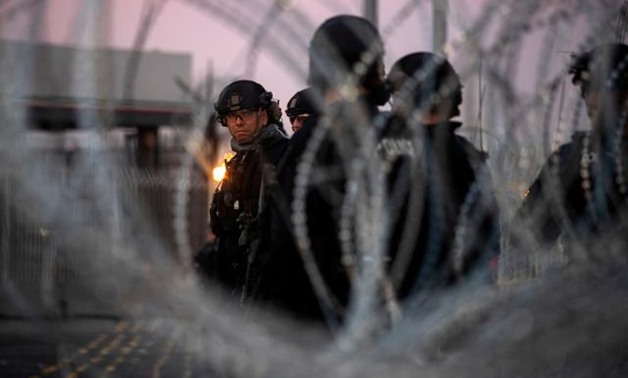 U.S. Customs and Border Protection (CBP) Special Response Team (SRT) officers are seen through concertina wire at the San Ysidro Port of Entry after the land border crossing was temporarily closed to traffic in Tijuana, Mexico November 19, 2018. REUTERS/A