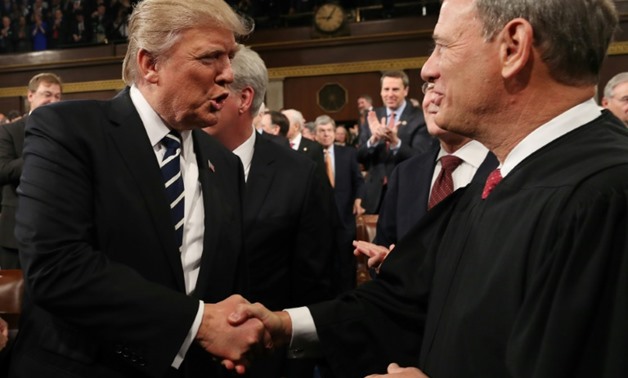 President Donald Trump shakes hands with US Supreme Court Chief Justice John Roberts

