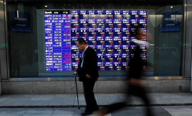 Passersby walk past in front of an electronic stock quotation board outside a brokerage in Tokyo, Japan, September 28, 2018. REUTERS/Toru Hanai
