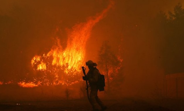 © Stephen Lam, REUTERS | A firefighter monitors a blaze near a home while battling the Camp Fire in Paradise, California on November 8, 2018.
