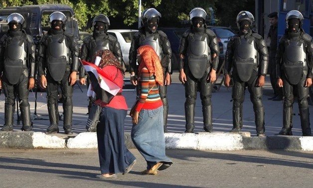 Girls walk past members of the riot police standing guard near a protest against sexual harassment in front of the opera house in Cairo June 14, 2014. REUTERS/Asmaa Waguih
