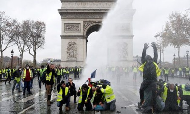 FILE PHOTO: Protesters wearing yellow vests, a symbol of a French drivers' protest against higher diesel taxes, stand up in front of a police water canon at the Place de l'Etoile near the Arc de Triomphe in Paris, France, December 1, 2018. REUTERS/Stephan