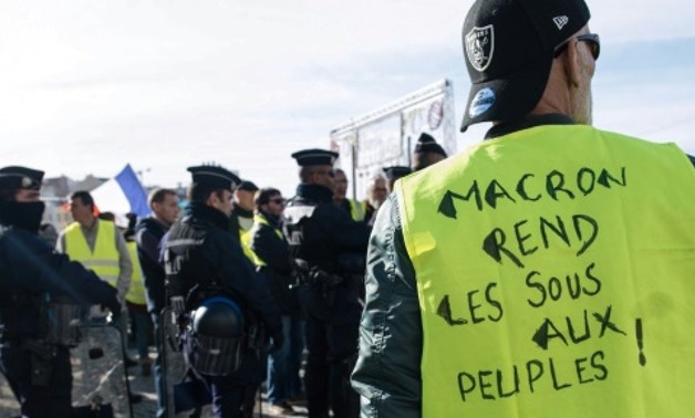 A "yellow vest" protester with the slogan "Macron, give the people their money back!" A "yellow vest" protester with the slogan "Macron, give the people their money back!" AFP
