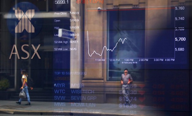 Pedestrians are reflected in a window in front of a board displaying stock prices at the Australian Securities Exchange (ASX) in Sydney, Australia, February 9, 2018. REUTERS/David Gray
