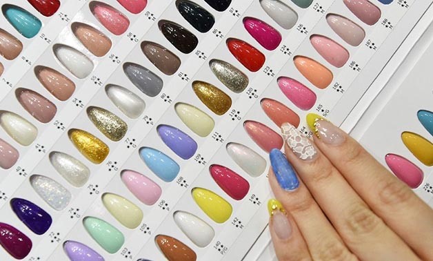 A nailist checks color samples of nail gel during this week's Tokyo Nail Forum, where catwalk models flashed their electric-pink digits and visitors dressed up their fingers in almost every imaginable way - AFP 