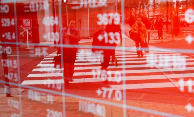 FILE PHOTO: Pedestrians are reflected on an electronic board showing stock prices outside a brokerage in Tokyo, Japan December 27, 2018. REUTERS/Kim Kyung-Hoon