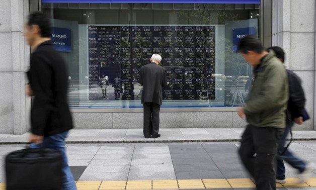 FILE PHOTO - A man looks at a stock quotation board outside a brokerage in Tokyo, Japan, April 18, 2016. REUTERS/Toru Hanai

