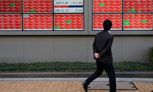 A man looks at an electronic board showing the Nikkei stock index outside

