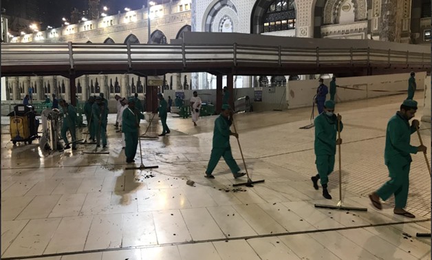 Workers cleaning the yard of the Great Mosque of Mecca after it had got infested with a big number of flying cockroaches - Press Photo  
