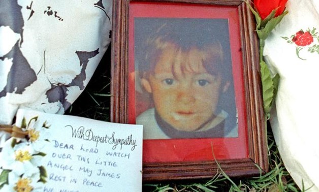 FILE PHOTO: A prayer and a red rose for murdered two-year-old toddler James Bulger, who appears in a picture among the floral tributes, are placed at the site of his murder in Liverpool, western England, February 20, 1993. REUTERS/Russell Boyce.